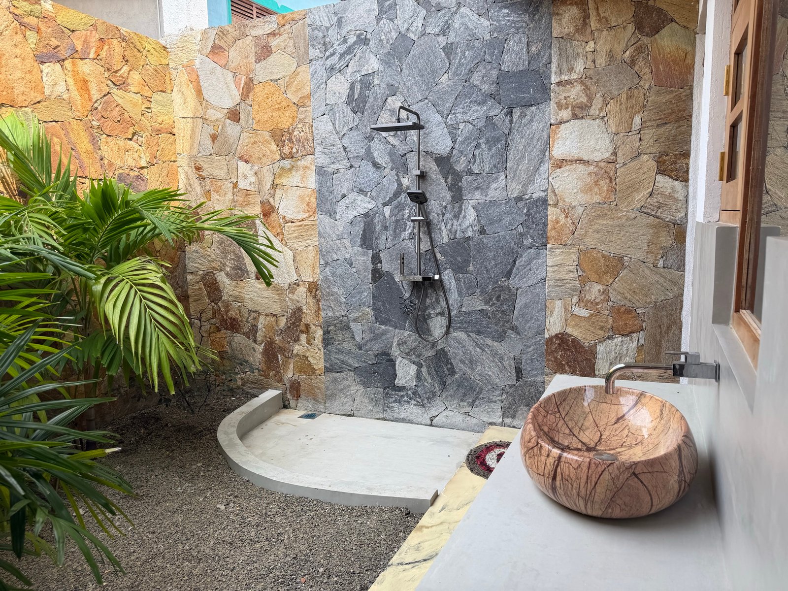 Large downstairs bedroom — private outdoor shower and basin among tropical plants. Separate indoor toilet and basin.